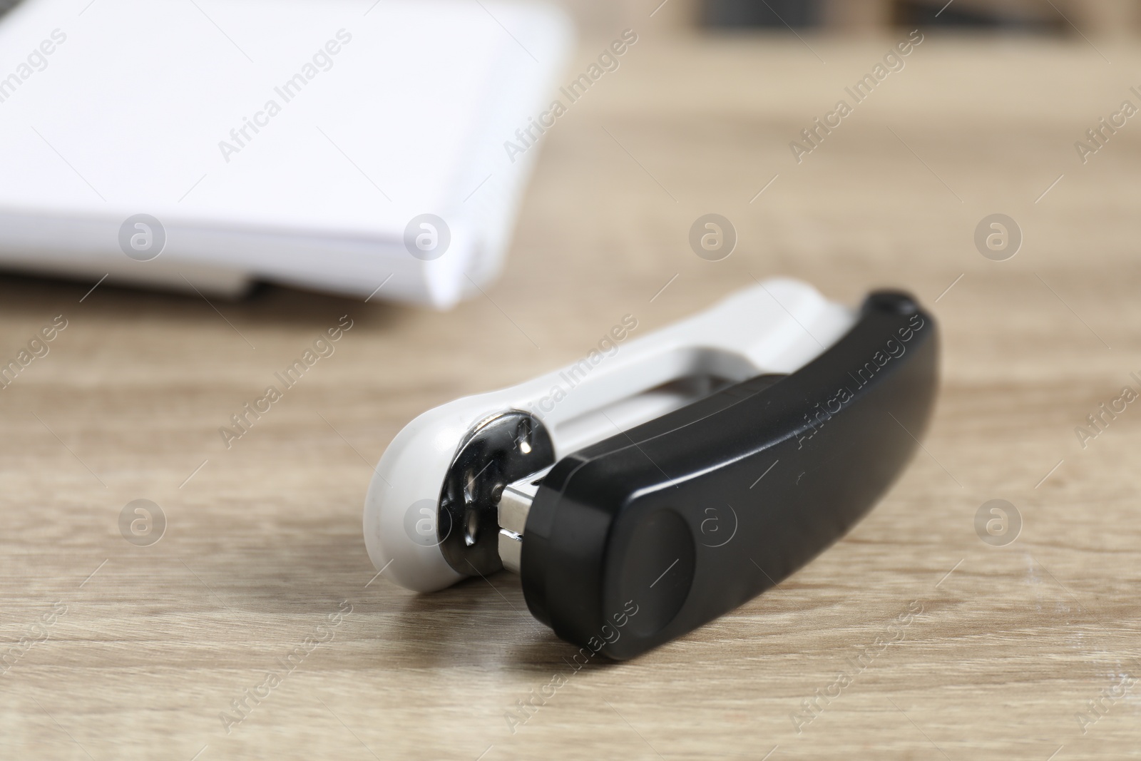 Photo of One stapler on wooden table, closeup view