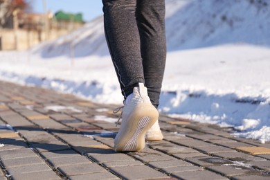 Woman running outdoors on winter day, closeup. Sports exercises
