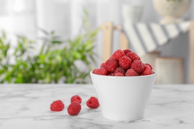 Bowl with ripe aromatic raspberries on table