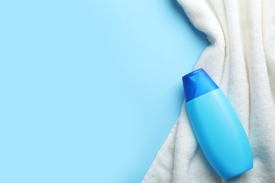 Photo of Bottle of shampoo and towel on color background, top view with space for text