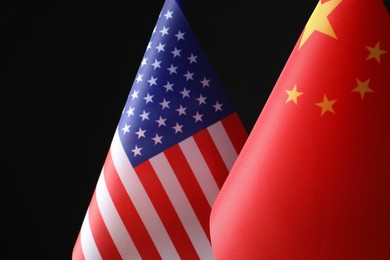 Photo of USA and China flags against black background, closeup. International relations