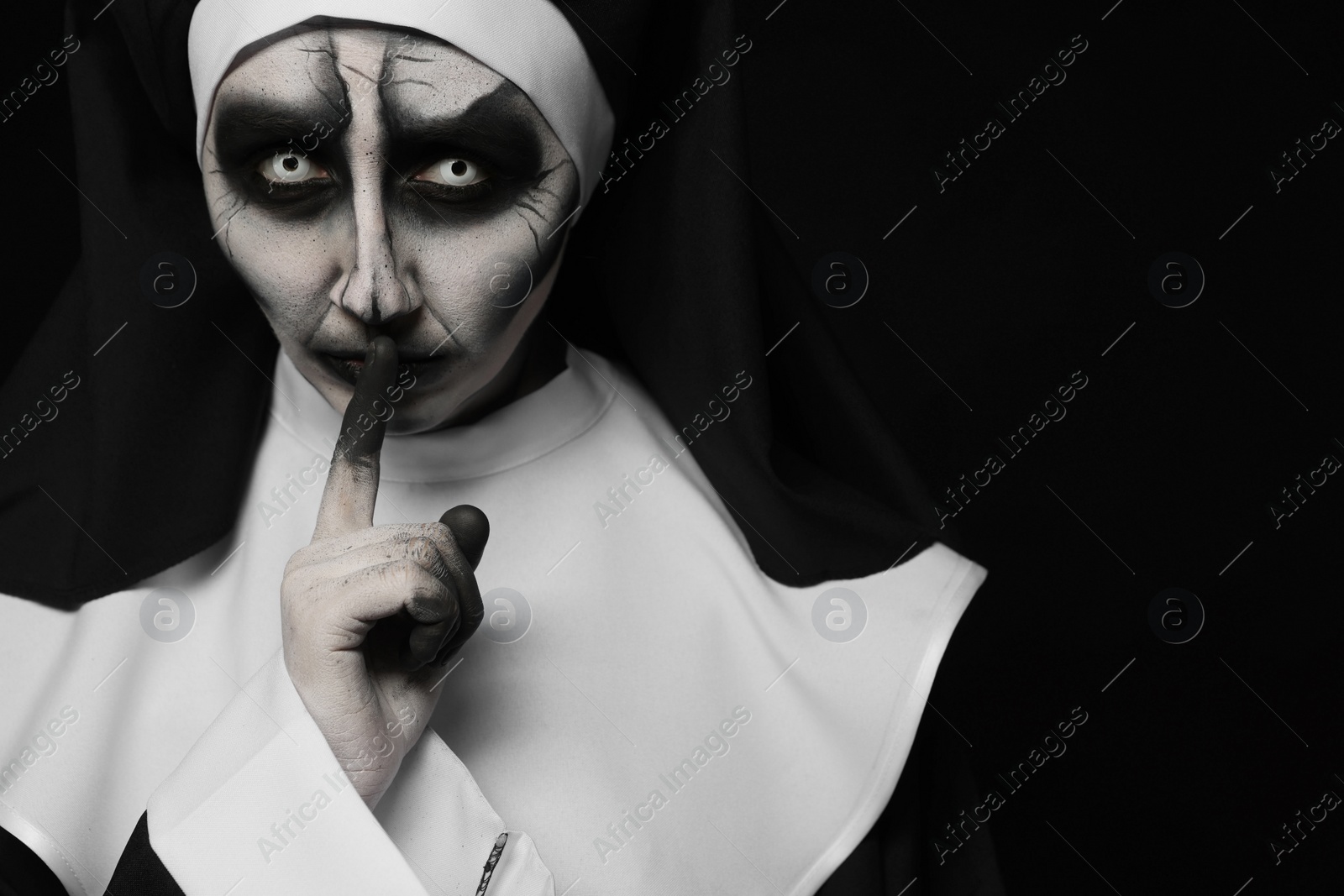 Photo of Portrait of scary devilish nun on black background, space for text. Halloween party look