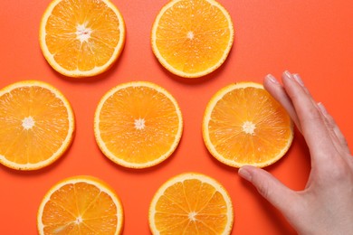 Photo of Woman with slices of juicy orange on terracotta background, top view