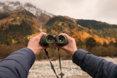 Boy holding binoculars in beautiful mountains, closeup