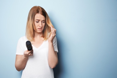 Young woman with hair loss problem on color background