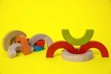 Photo of Colorful wooden pieces of playing set on yellow background. Educational toy for motor skills development