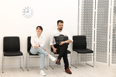 Photo of Man and woman waiting for job interview indoors