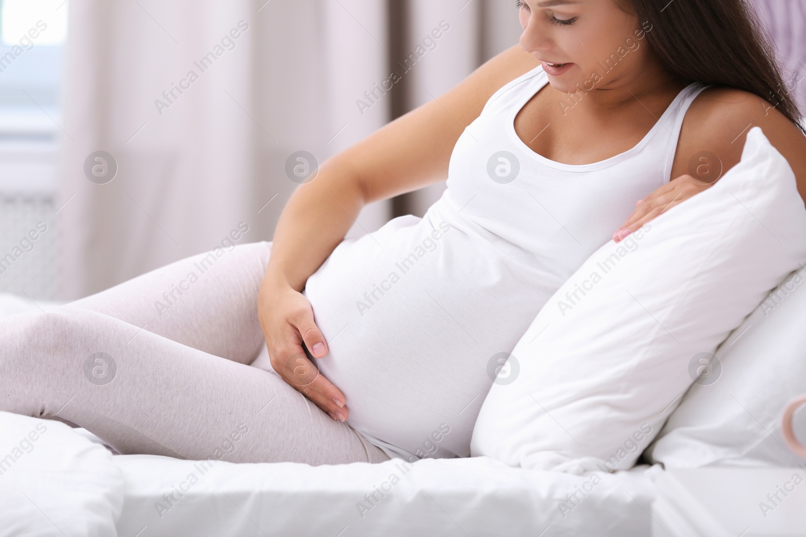 Photo of Happy pregnant woman lying on bed at home, closeup