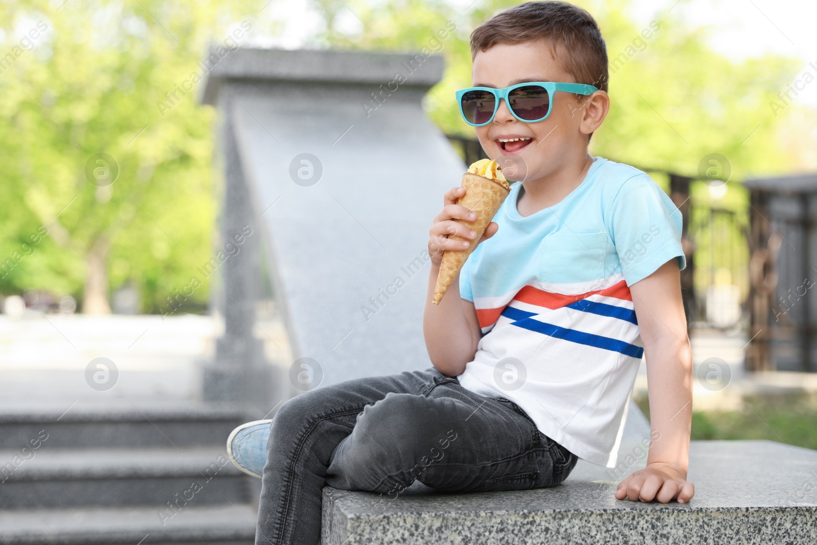 Photo of Cute little boy with delicious ice cream outdoors, space for text