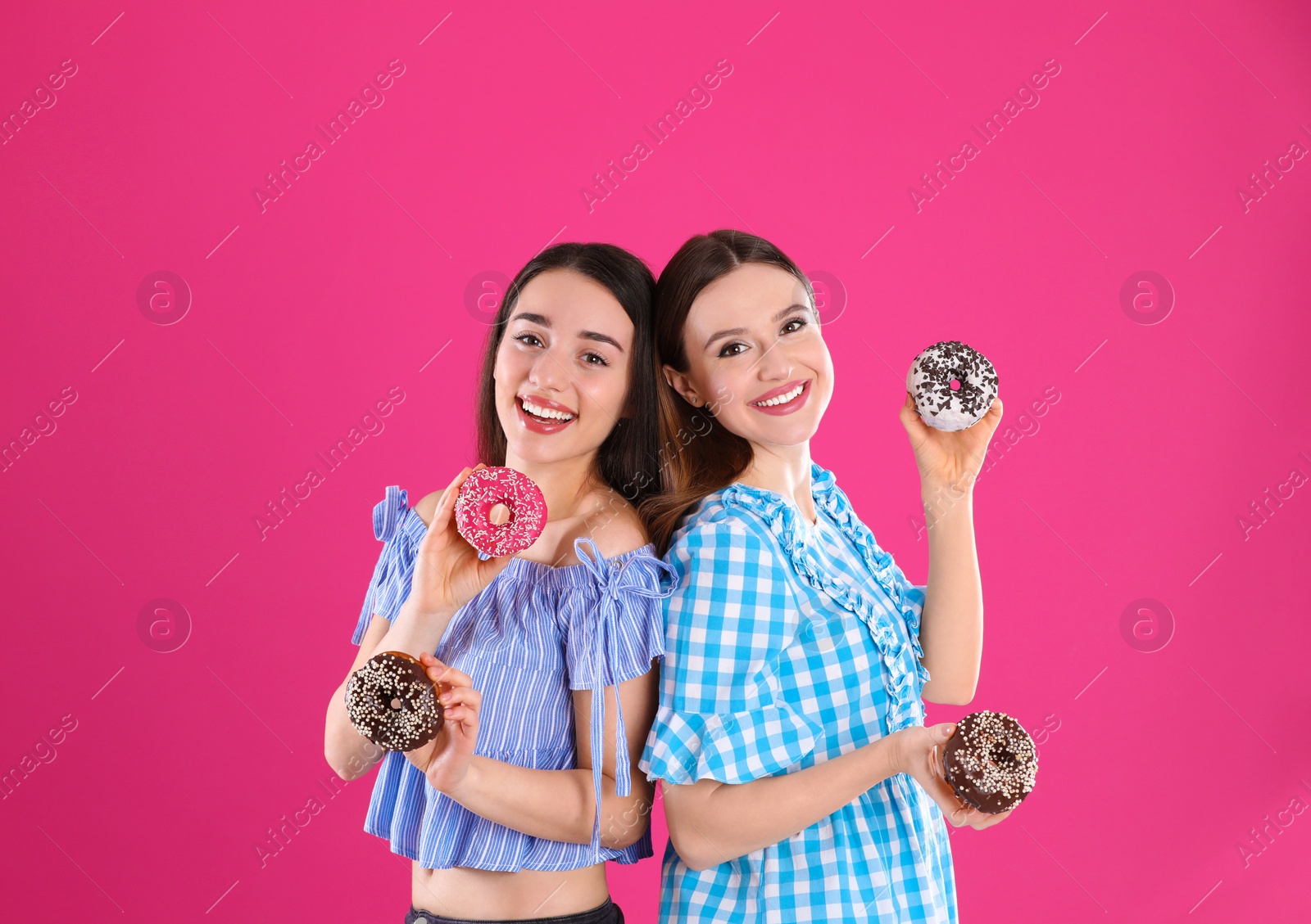 Photo of Beautiful young women with donuts on pink background