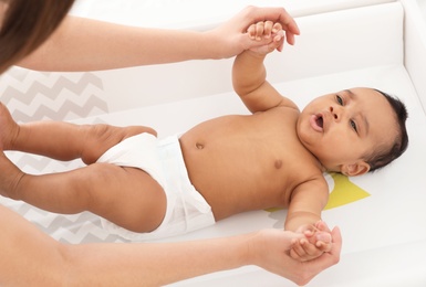 Photo of Mother and her cute child on changing table, above view. Baby massage and exercises