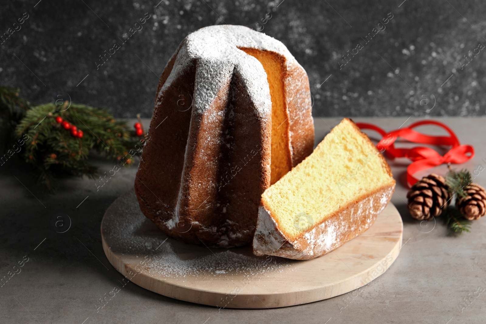 Photo of Delicious Pandoro cake with powdered sugar and Christmas decor on grey table