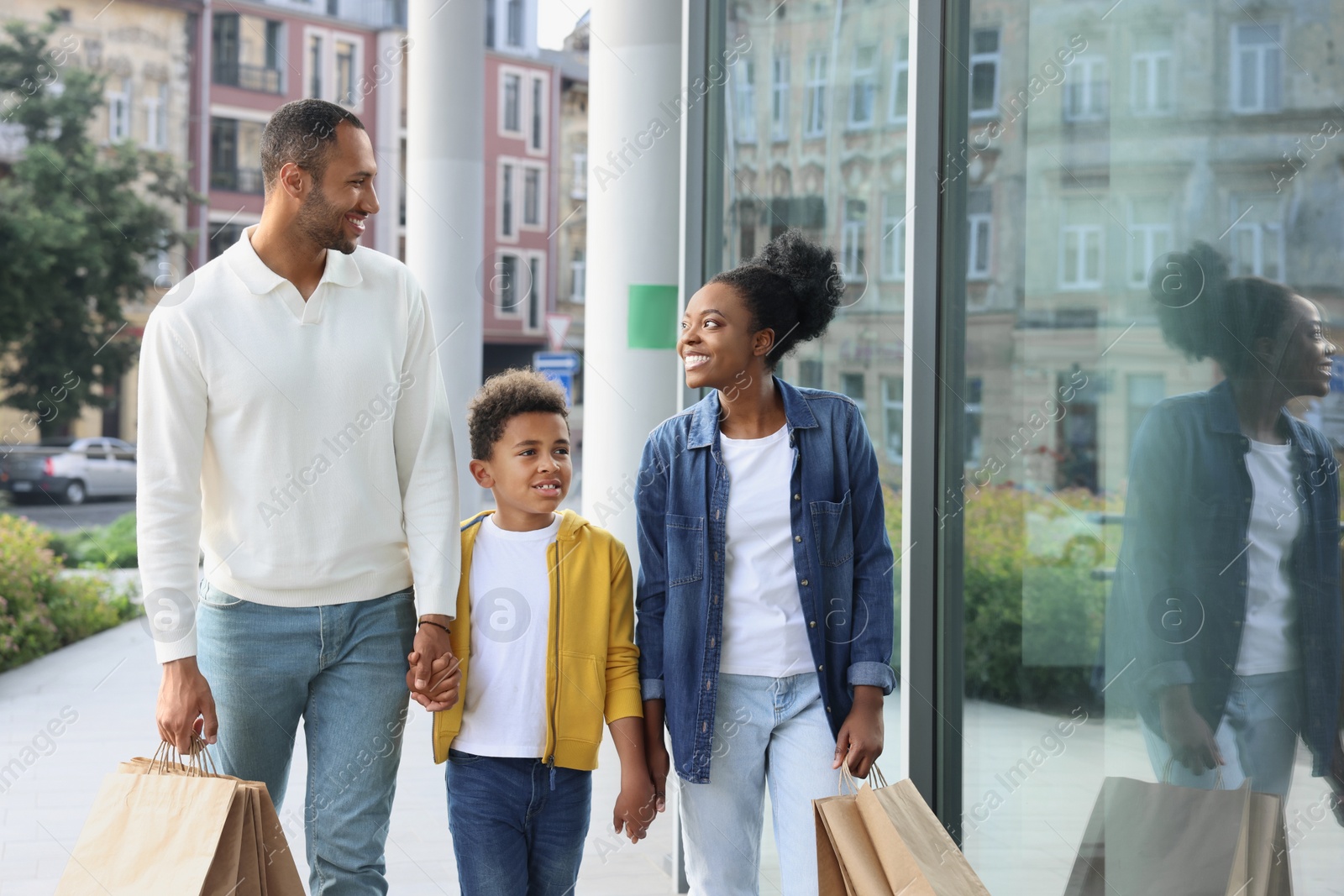 Photo of Family shopping. Happy parents and son with purchases near mall outdoors