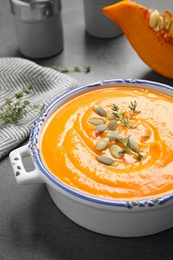 Photo of Delicious pumpkin soup in bowl on grey table, closeup