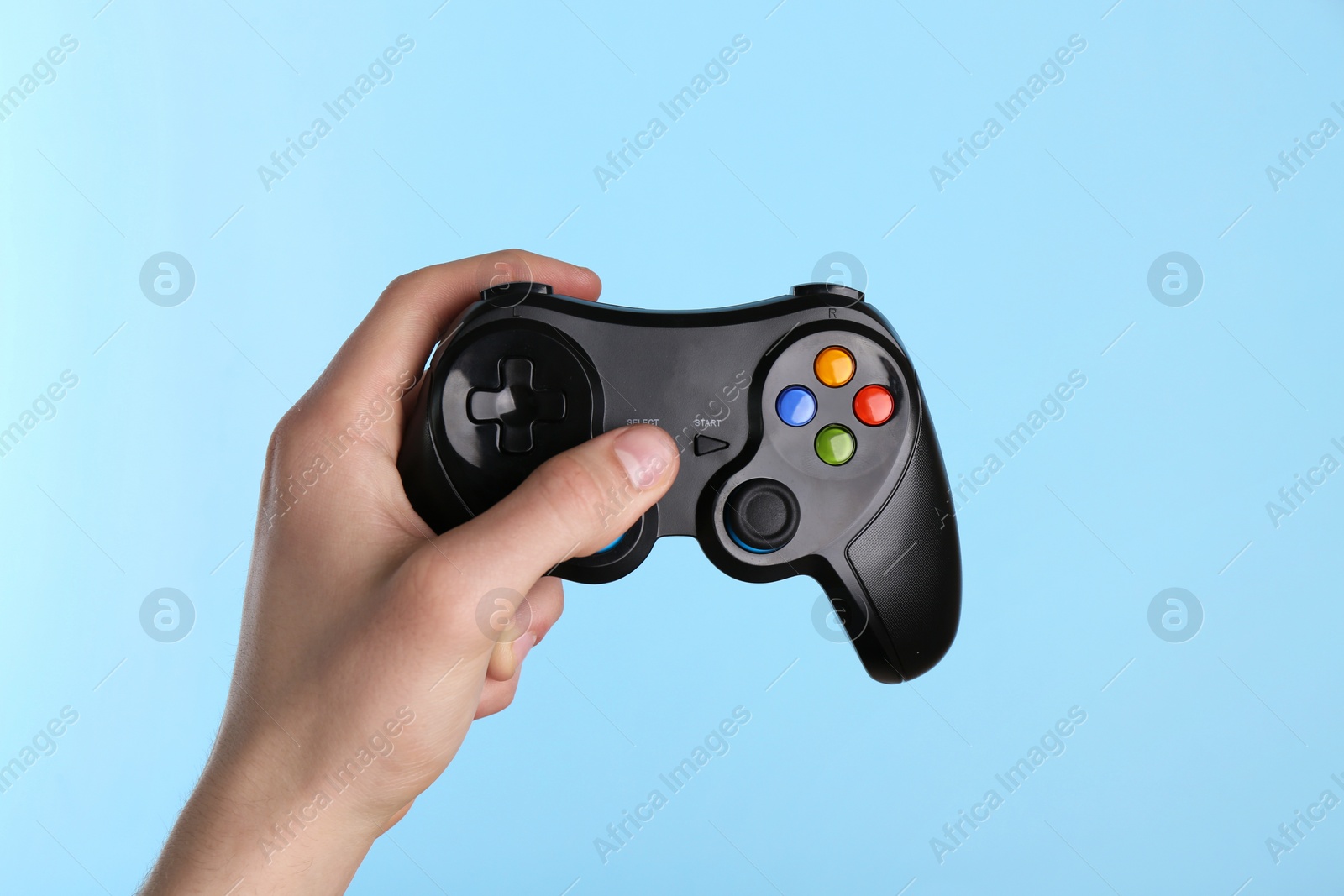 Photo of Man using wireless game controller on light blue background, closeup