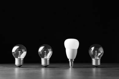 Photo of Incandescent and LED lamp bulbs on grey table against black background