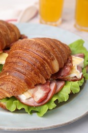 Photo of Tasty croissant with brie cheese, ham and bacon on table, closeup