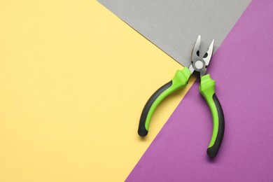 Photo of Combination pliers on color background, top view. Space for text