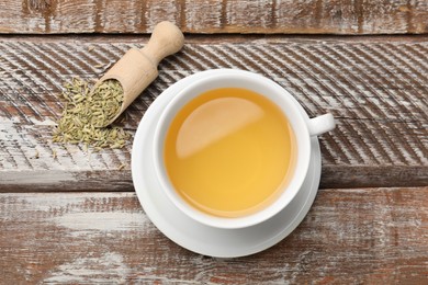 Photo of Aromatic fennel tea, seeds and scoop on wooden table, top view