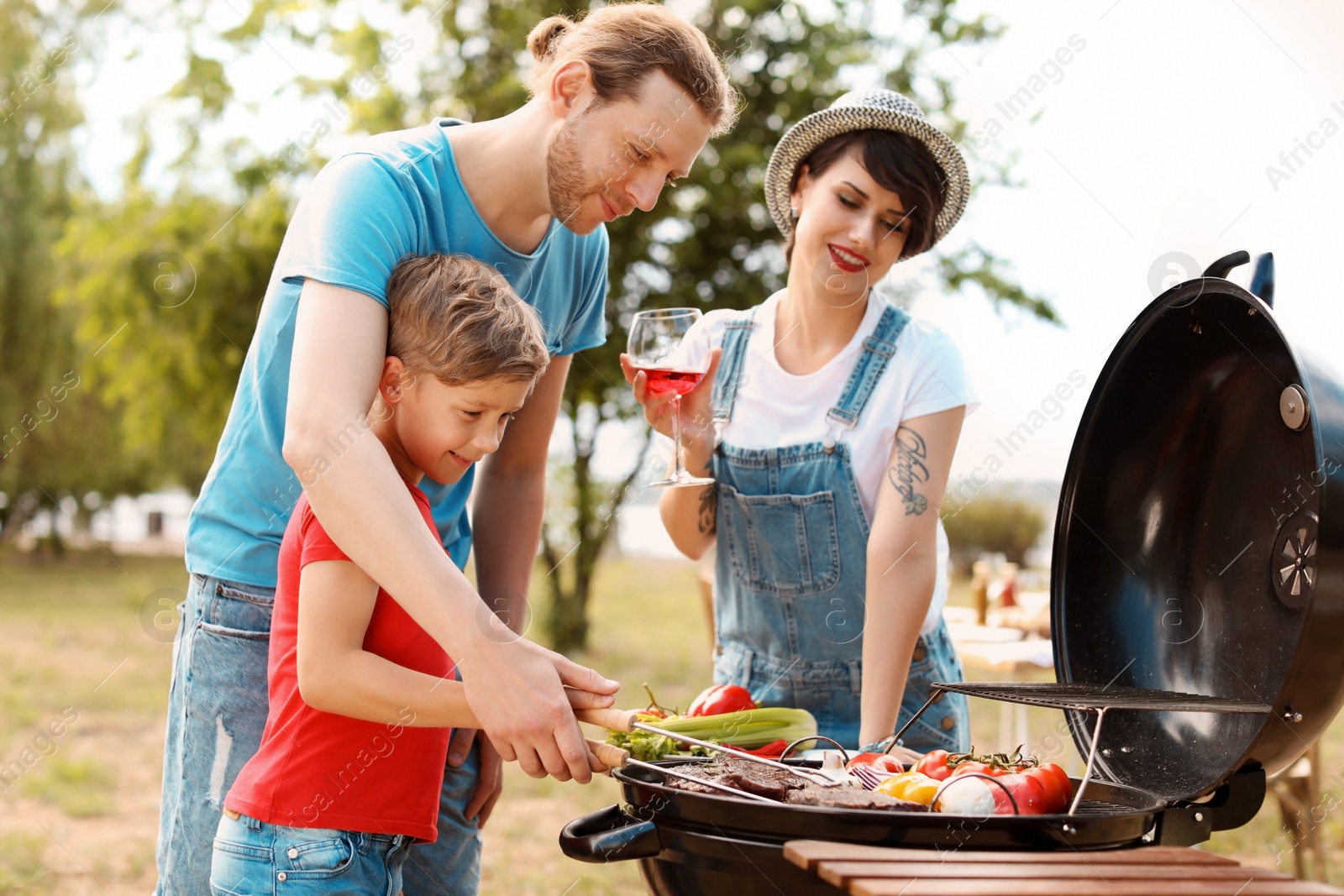 Photo of Happy family having barbecue with modern grill outdoors