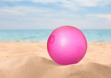 Image of Pink beach ball on sandy coast near sea 