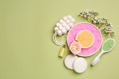 Photo of Sea salt, soap bars and beautiful flowers on olive background, flat lay. Space for text