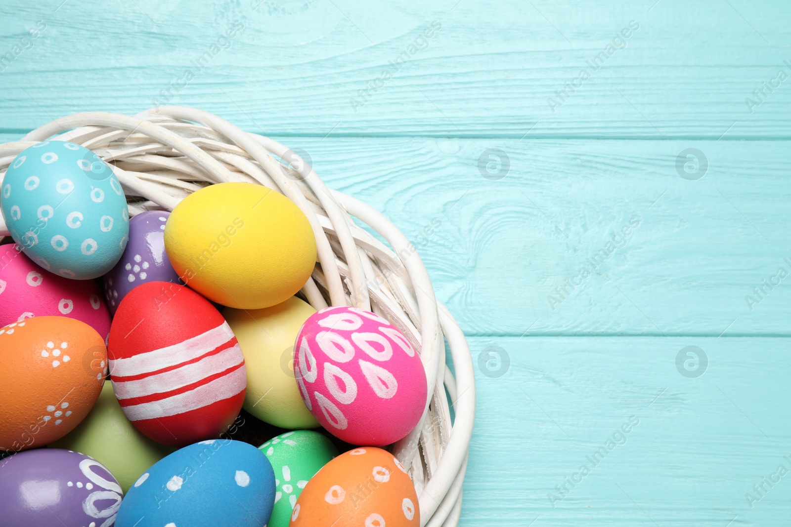 Photo of Colorful Easter eggs on light blue wooden background, top view. Space for text