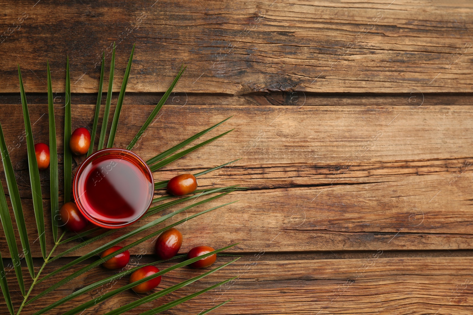 Photo of Palm oil in glass, tropical leaf and fruits on wooden table, flat lay. Space for text