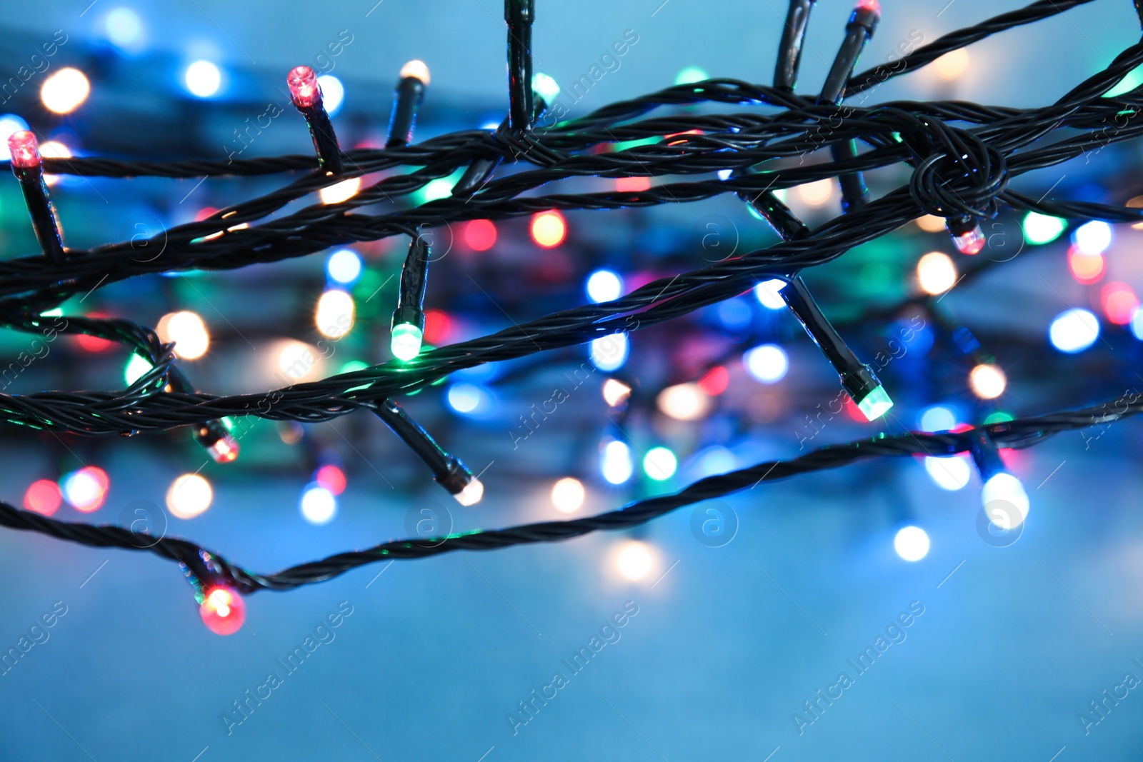 Photo of Beautiful Christmas lights on color background, closeup