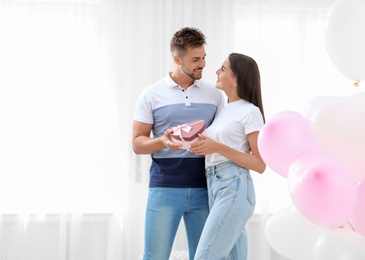 Young couple in room decorated with air balloons. Celebration of Saint Valentine's Day