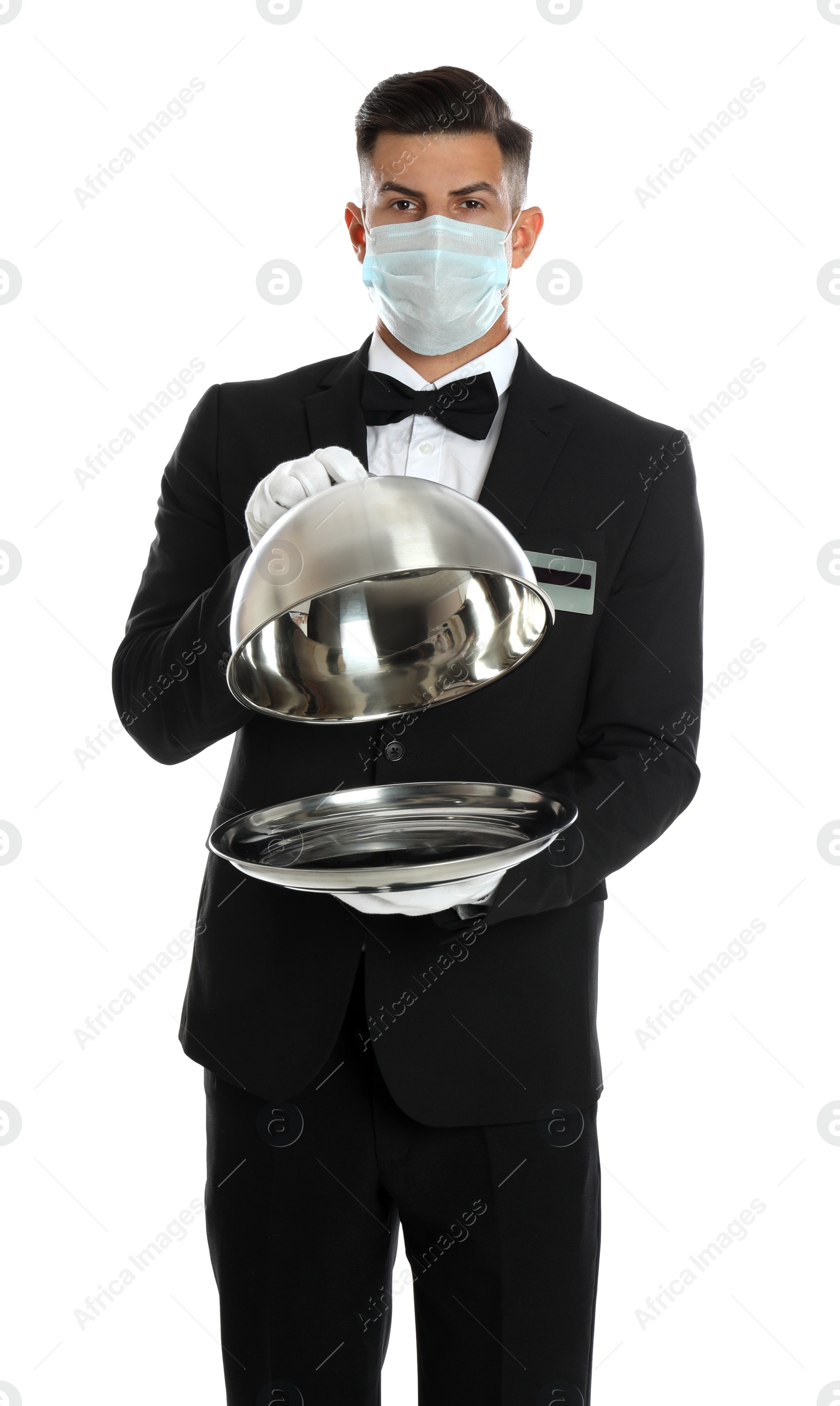 Photo of Waiter in medical face mask holding tray with lid on white background