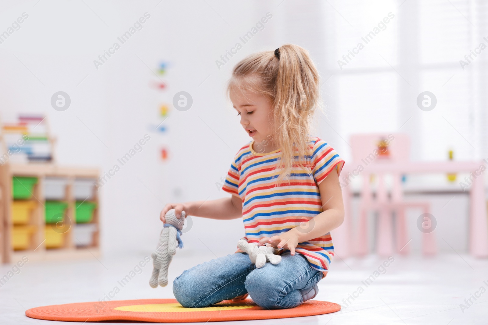 Photo of Cute little child playing with knitted toys on floor at home