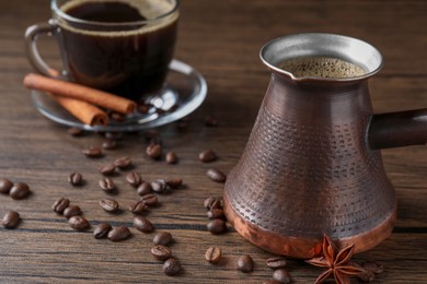 Photo of Turkish coffee in cezve and cup, beans and spices on wooden table. Space for text