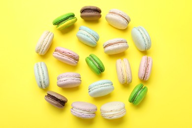 Photo of Delicious colorful macarons on yellow background, flat lay