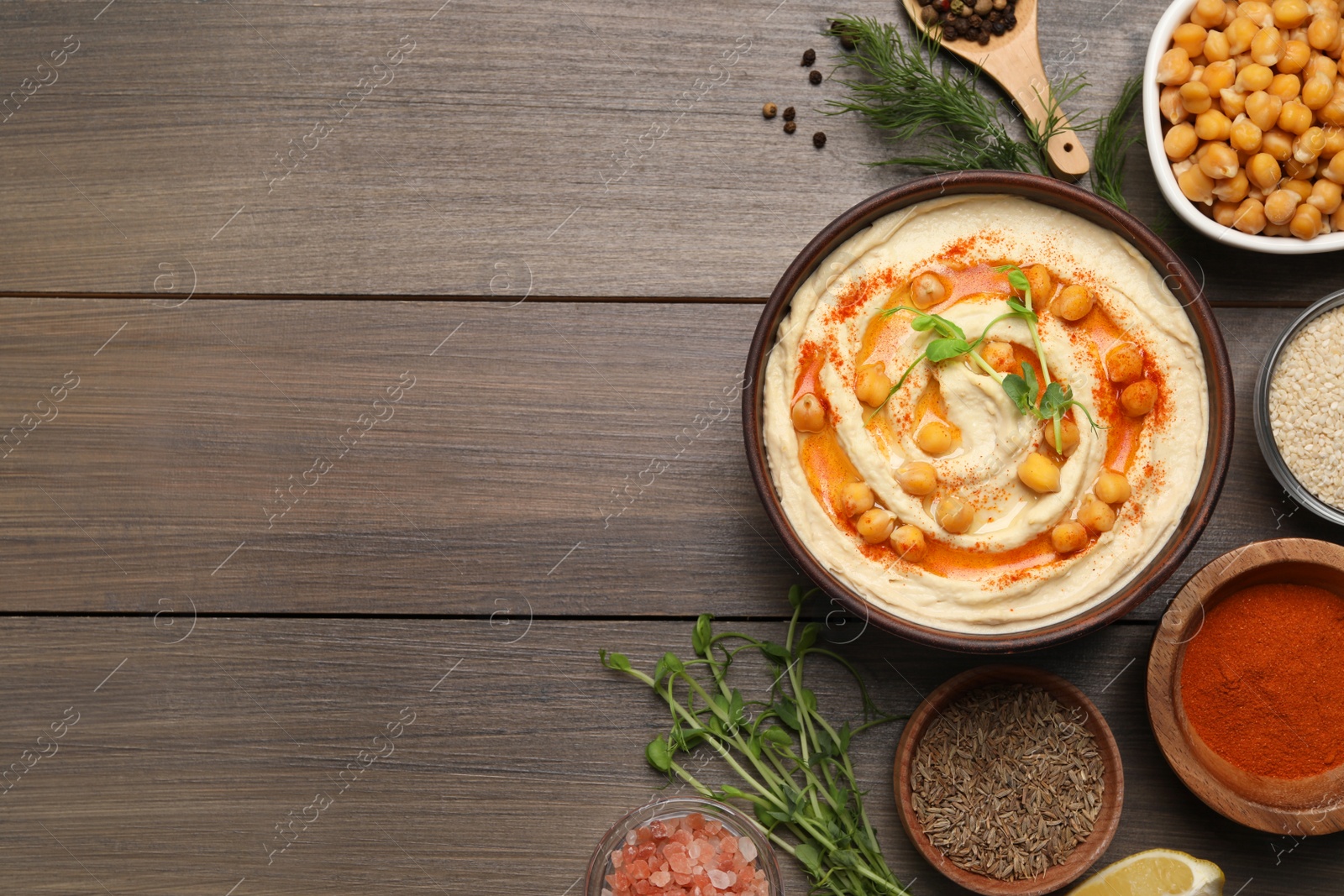 Photo of Delicious hummus with chickpeas and different ingredients on wooden table, flat lay. Space for text