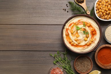 Photo of Delicious hummus with chickpeas and different ingredients on wooden table, flat lay. Space for text