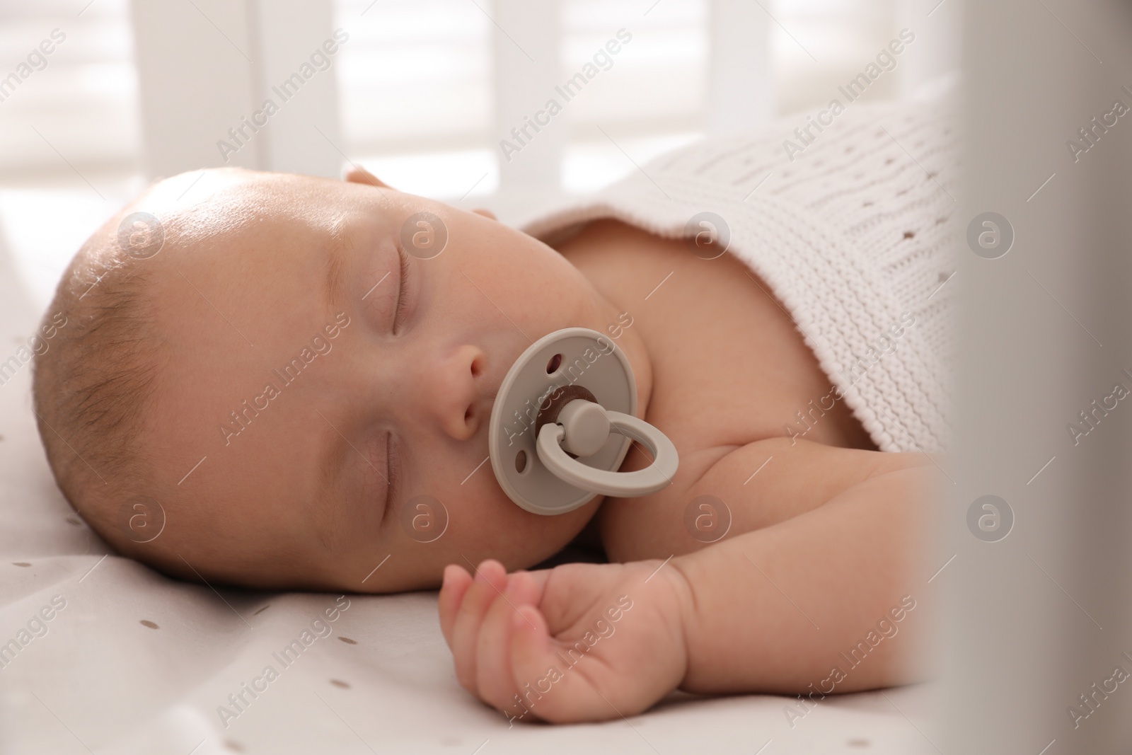 Photo of Cute little baby with pacifier sleeping in crib, closeup