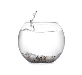 Photo of Splash of water in round fish bowl with decorative pebbles on white background