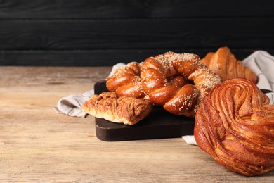 Different tasty freshly baked pastries on wooden table, space for text
