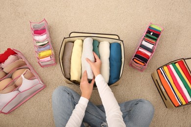 Photo of Woman folding clothes on floor, top view. Japanese storage system