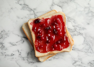 Slice of bread with jam on white marble table, top view