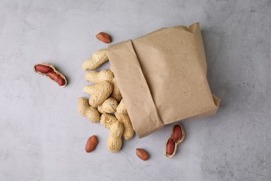 Photo of Paper bag with fresh unpeeled peanuts on grey table, top view