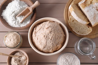 Fresh sourdough, flour, water and bread on wooden table, flat lay