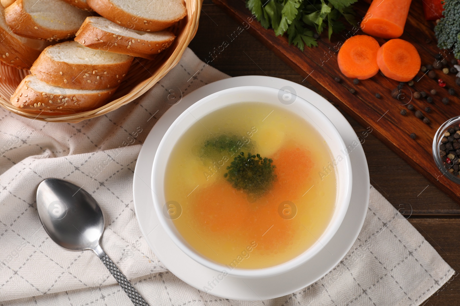 Photo of Tasty soup with vegetables in bowl served on wooden table, flat lay