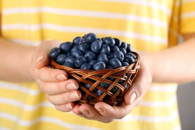 Photo of Woman holding tasty fresh blueberries, closeup view