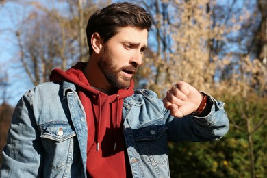 Photo of Man checking time on watch outdoors. Being late concept