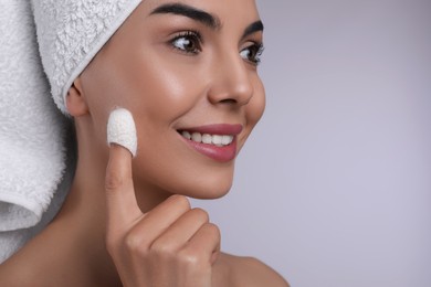 Woman using silkworm cocoon in skin care routine on light grey background, closeup. Space for text