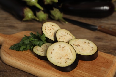 Photo of Cut raw ripe eggplant and parsley on wooden board