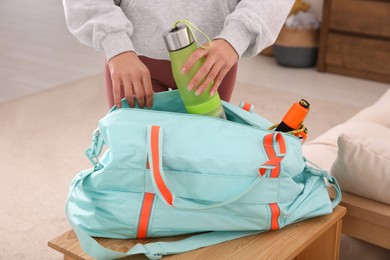 Woman packing sports stuff for training into bag at home, closeup