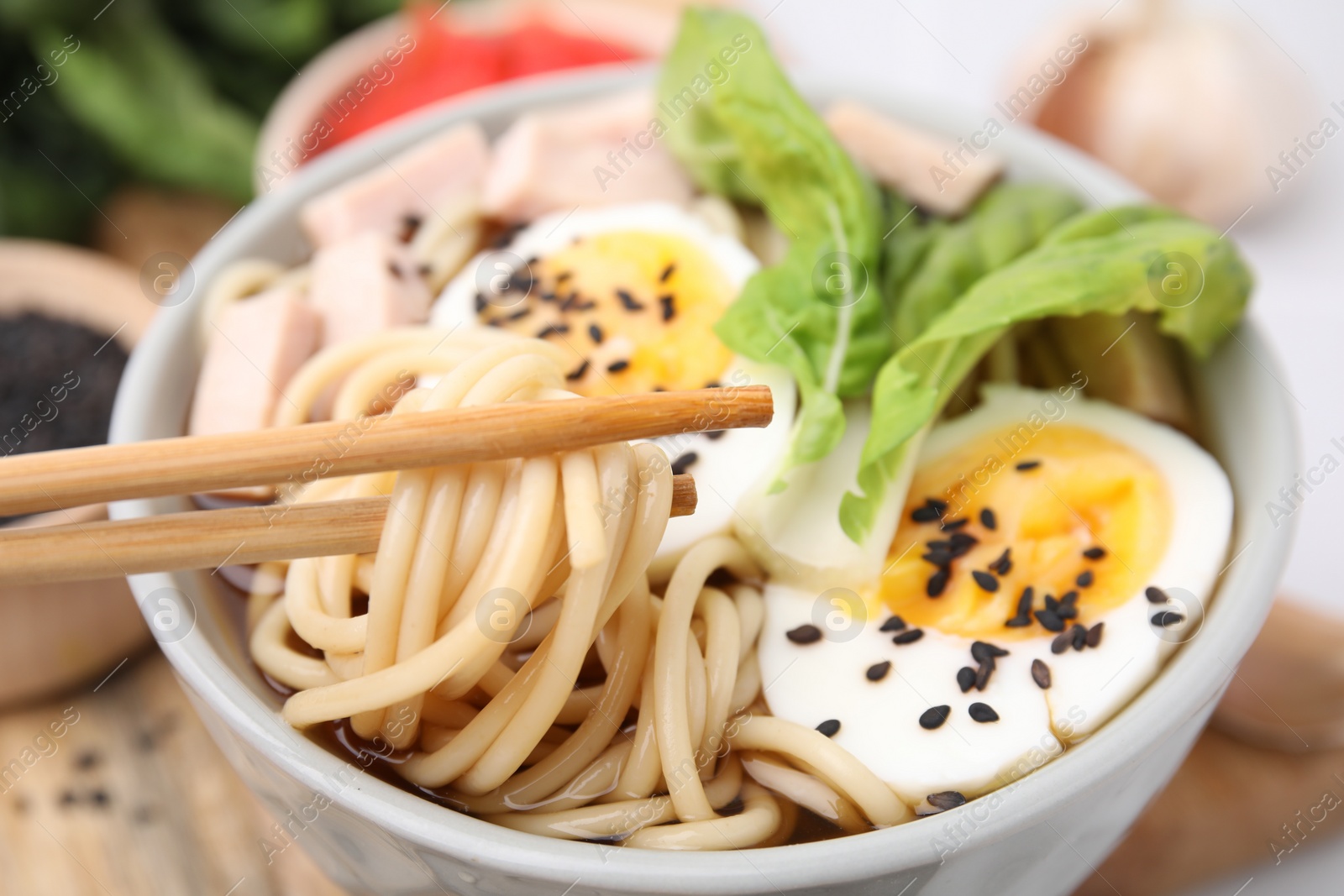 Photo of Eating delicious ramen from bowl with chopsticks, closeup. Noodle soup